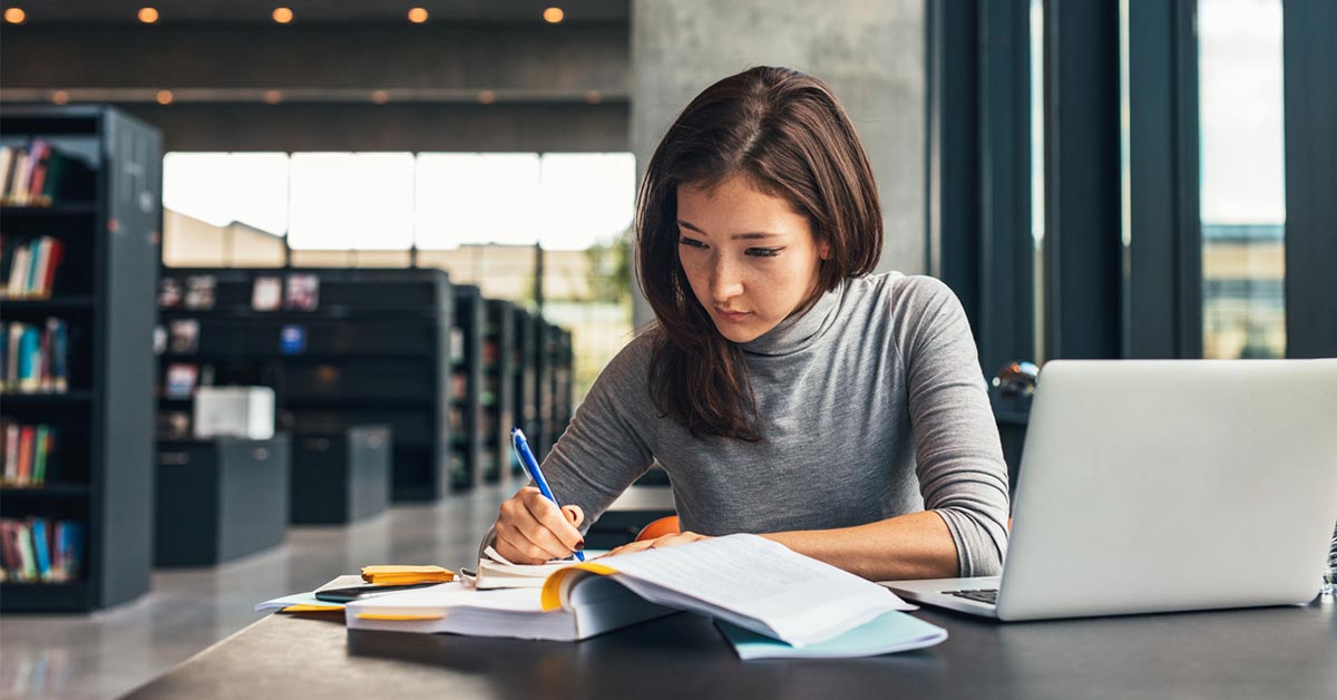 Image shows a student sitting at a table studying.